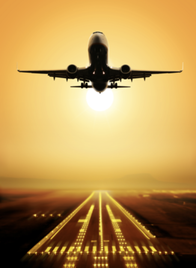 Verkehrsflugzeug über einer beleuchteten Startbahn im goldenen Abendlicht